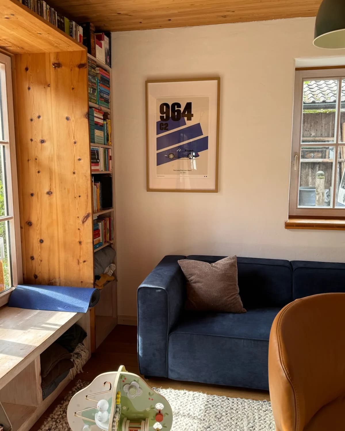 The framed Heckblick poster of the 964 above a blue sofa in Moritz's living room